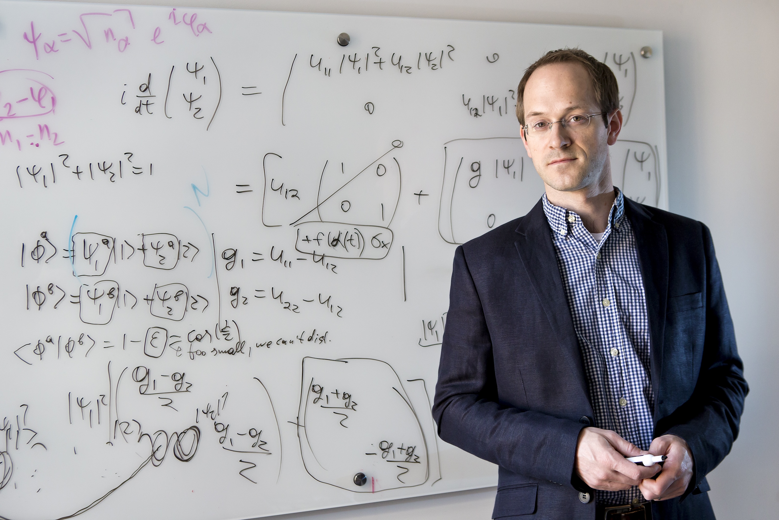 Andrew Childs stands in front of a white board with equations.