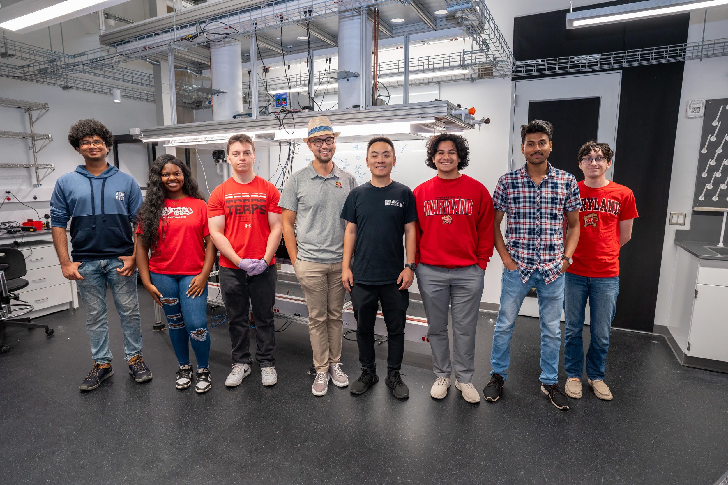 Eight people stand in a row with clean white laboratory space behind them.